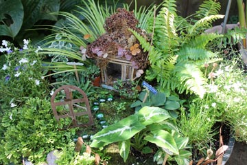 This fairy garden is an outdoor, in-ground model that uses a traditional woodland theme.